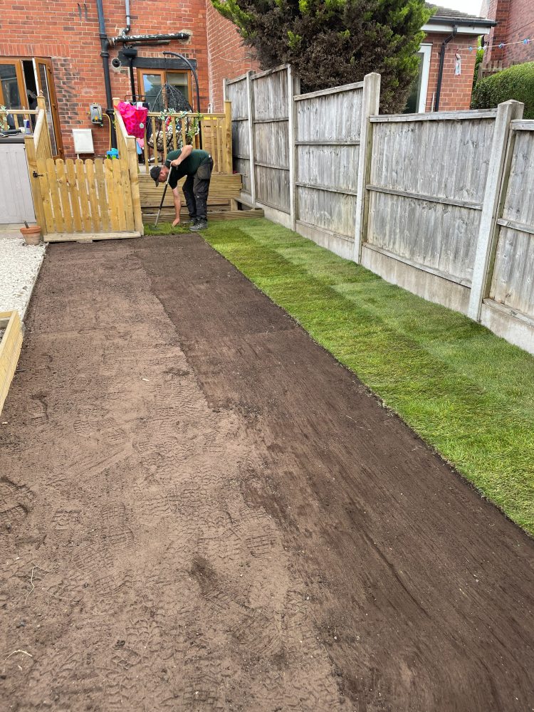 Fresh turf being laid on a prepared, levelled soil bed in a Leeds garden