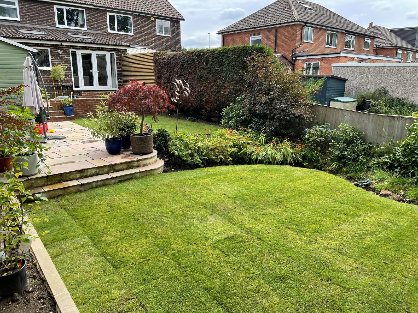 New lawn installation beside patio steps and mature planting
